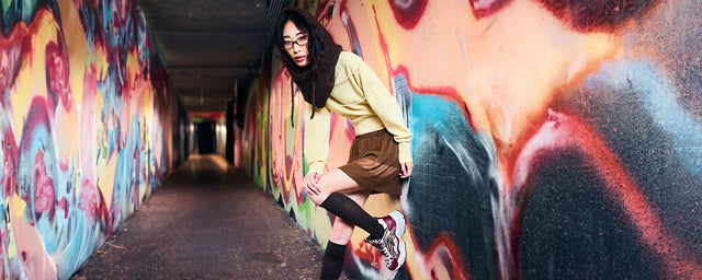 Donna appoggiata ad un muro con graffiti indossando scarpe buffalo