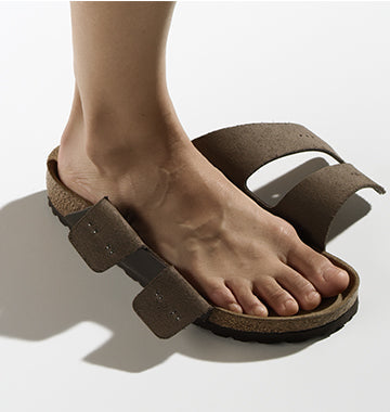 Sandalo Birkenstock Arizona marrone con le due fasce aperte, indossato da una persona con il piede correttamente posizionato all'interno del plantare.