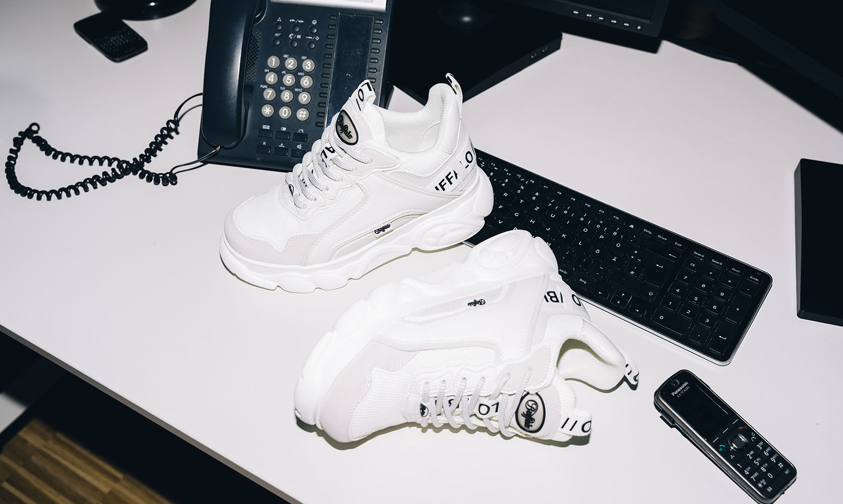 Sneakers Buffalo CLD Chai Donna Vegan total white appoggiate su una scrivania.