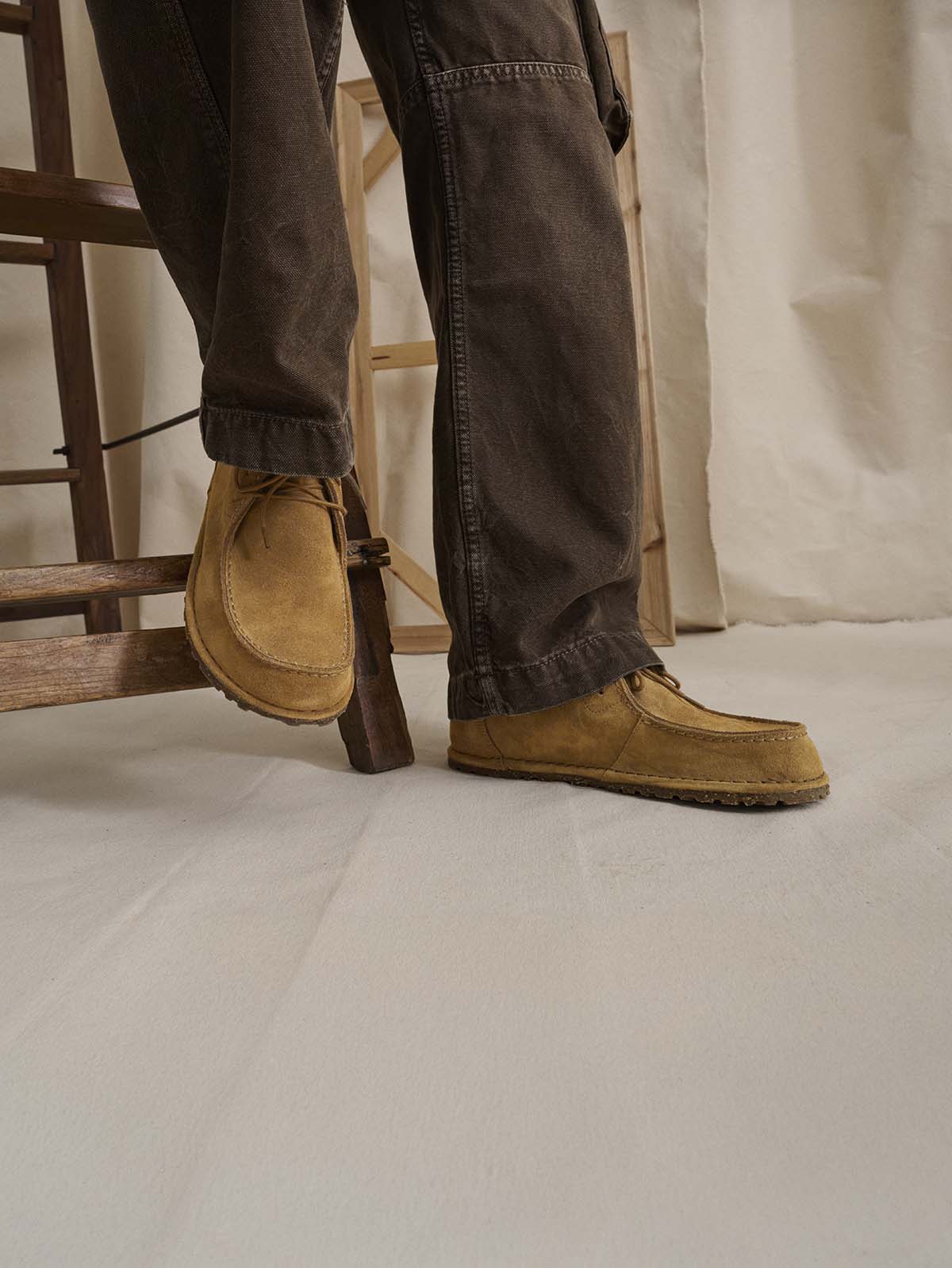 mocassini scarpe birkenstock utti cork indossate da persona appoggiata a una scala di legno