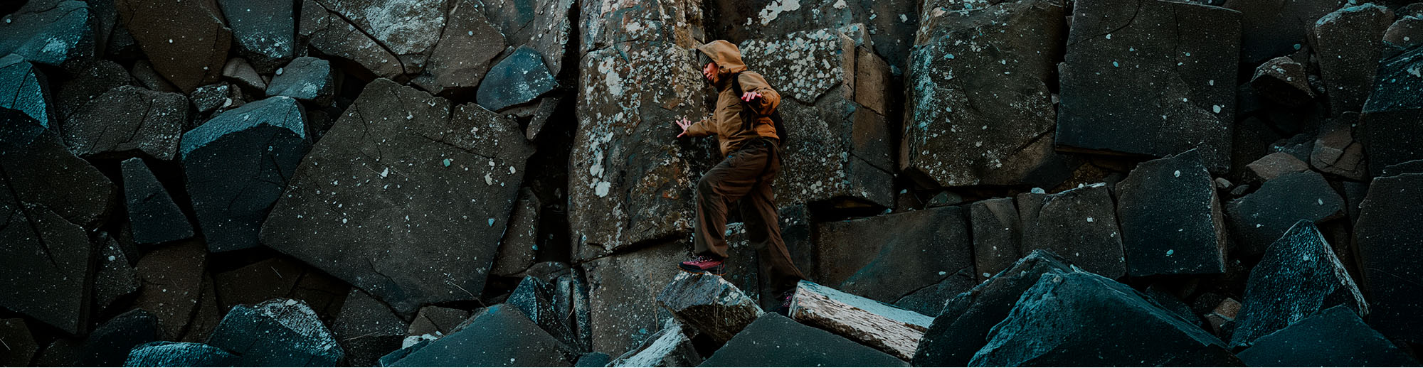 KEEN Jasper Zionic indossate mentre una persona si muove tra grandi rocce, in una scena outdoor che richiama performance e versatilità.