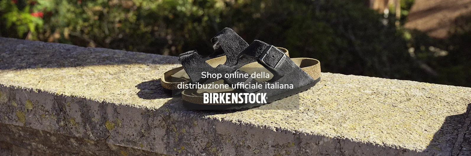 primo piano di arizona birkenstock sandali charcoal appoggiati su muretto in un parco