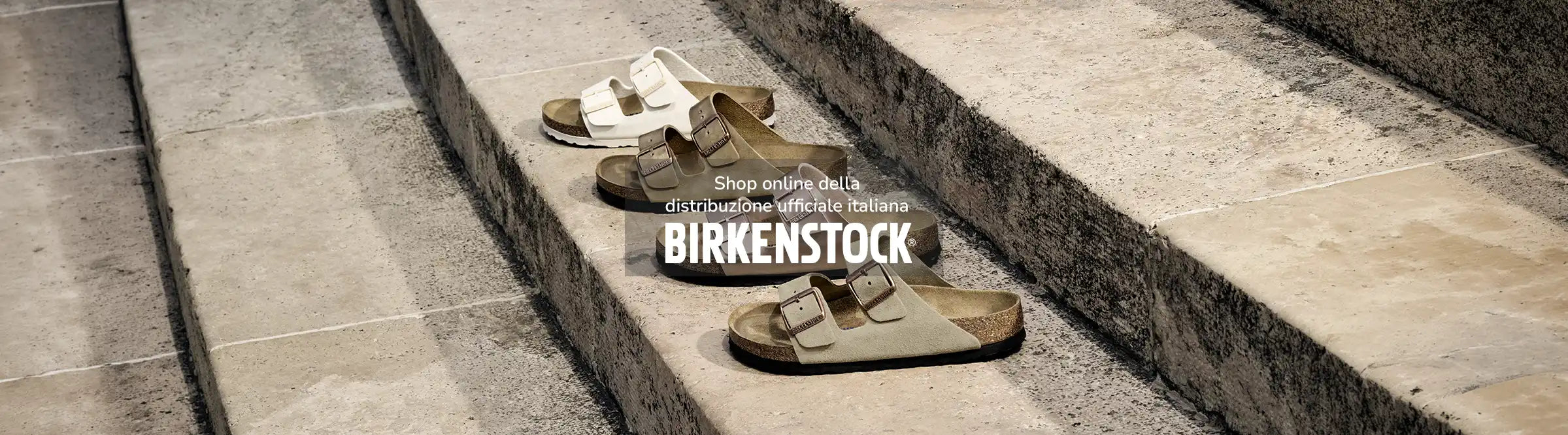 Sandali birkenstock Arizona in quattro colorazioni differenti: eggshell, tabacco, copper e taupe appoggiate su una scala in pietra