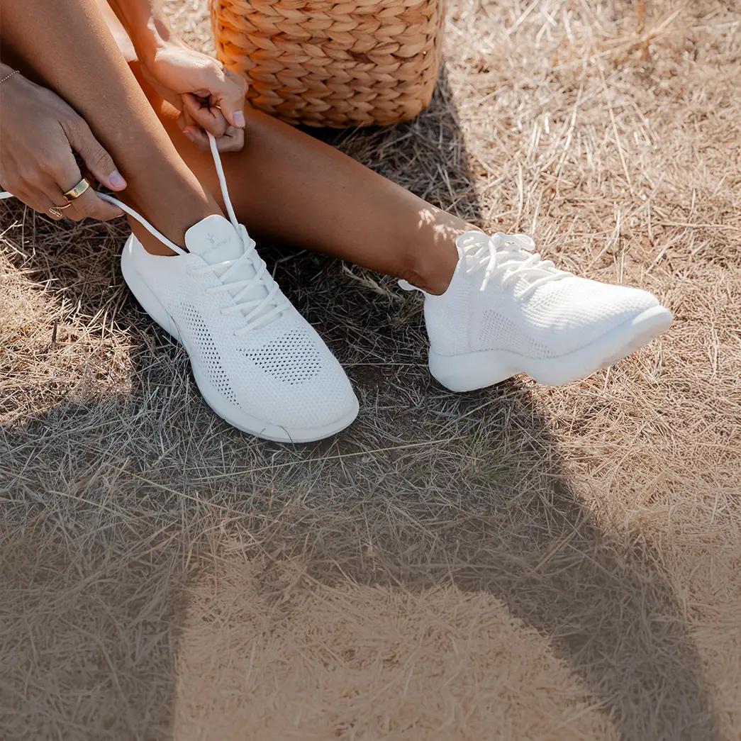primo piano di scarpe emu australia modello miki bianco indossate da donna seduta su paglia