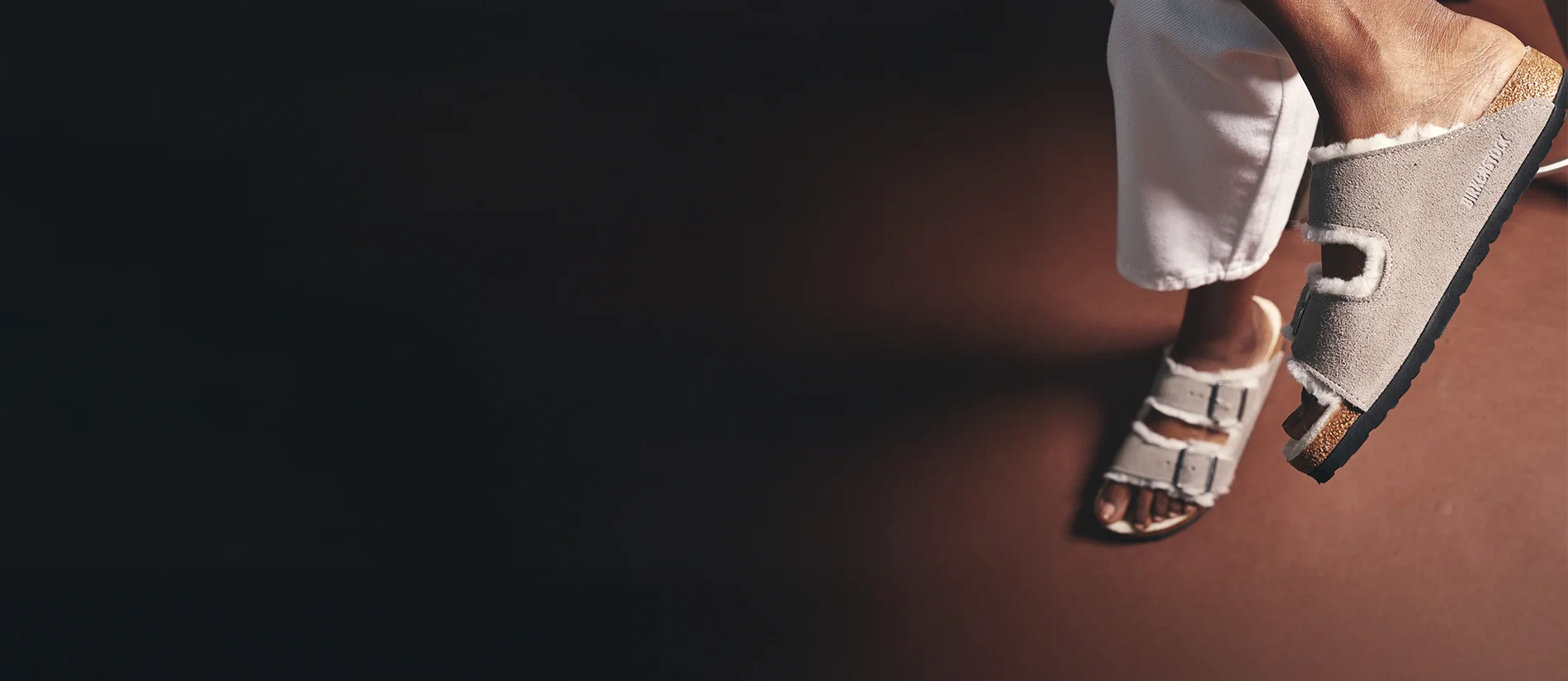 Primo piano di arizona sandali birkenstock shearling taupe viste dall'alto indossate con focus di un sandalo laterale con scritta birkenstock