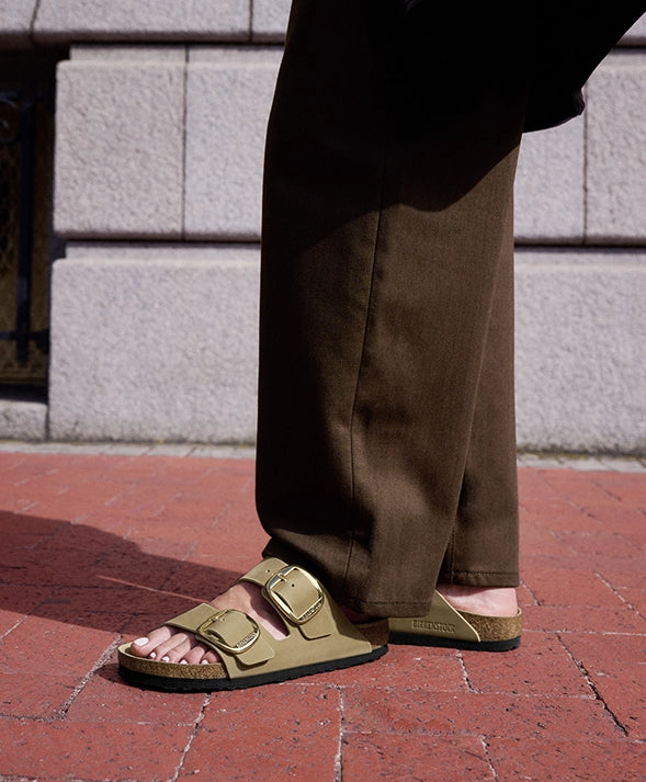 Primo piano laterale di sandali birkenstock big buckle tabacco brown indossate da donna con scarpe 