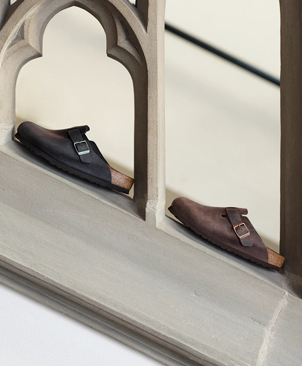 Due paia di boston birkenstock sabot appoggiate su una scala di marmo viste lateralmente