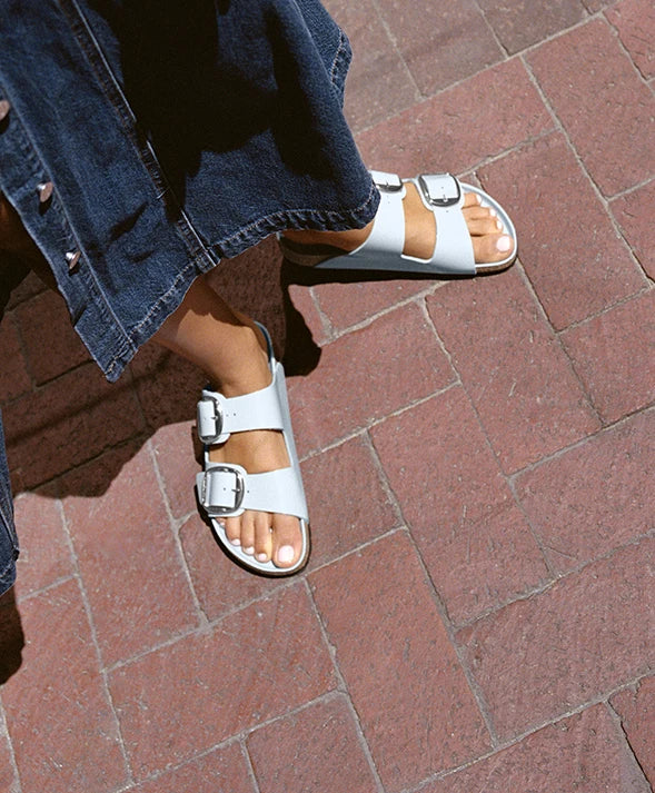 Primo piano dall'alto di sandali arizona shine big buckle indossate da donna con vestito di jeans