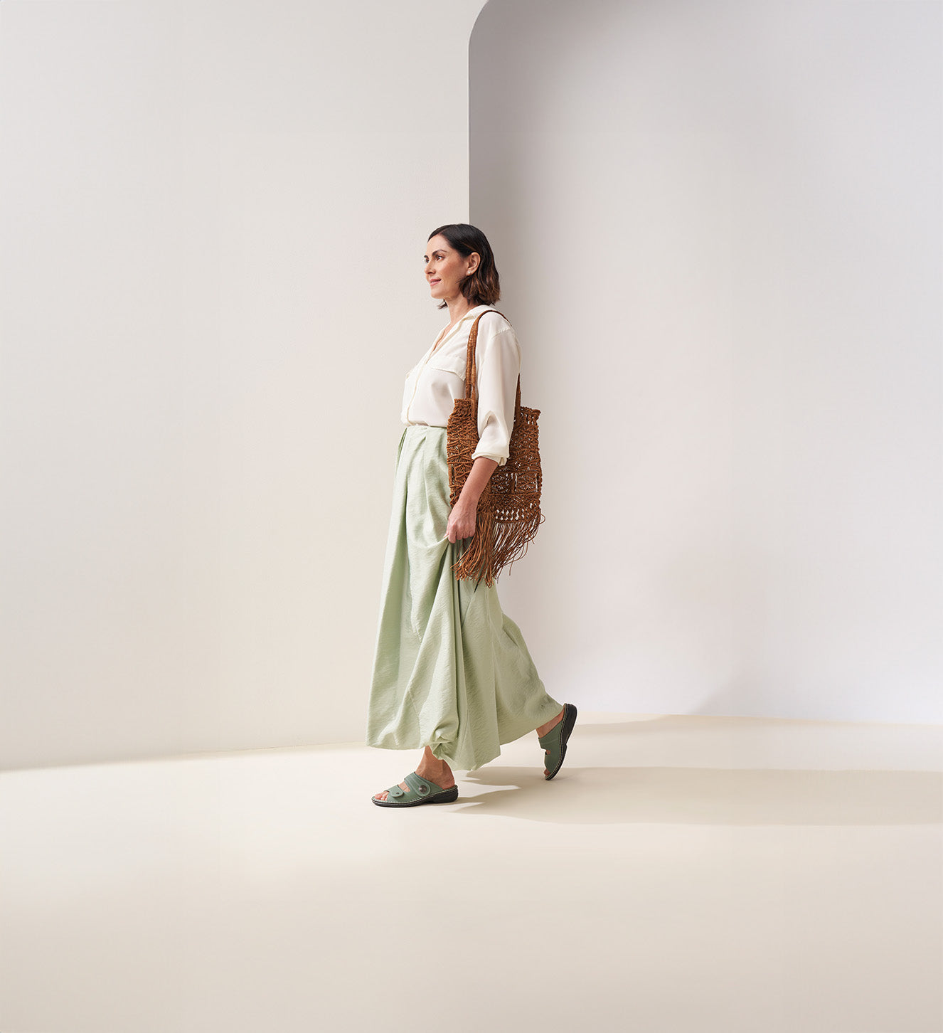 Donna che cammina con sandali FinnComfort verdi, ideali per uso quotidiano e benessere del piede