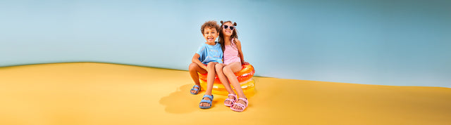 bambino e bambina su sfondo colorato che indossano sandali birkenstock eva