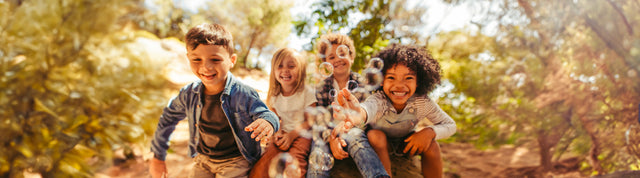 bambini che giocano con bolle di sapone in mezzo alla natura