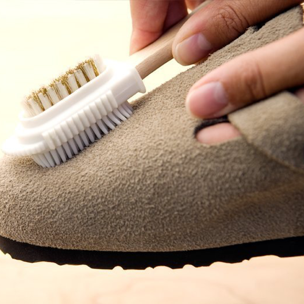 Primo piano della pulizia del Birkenstock Boston Sabot Unisex in pelle scamosciata color taupe, con spazzola di gommini.